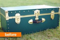 an old green trunk sitting in the grass with gold trimming on it's handles