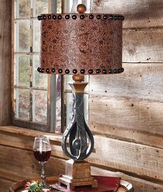 a lamp that is on top of a table next to a wine glass and bottle