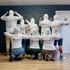 a group of people in white hoodies sitting on the floor with their backs to each other