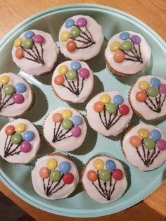 cupcakes with white frosting and balloons on them are arranged in a circle