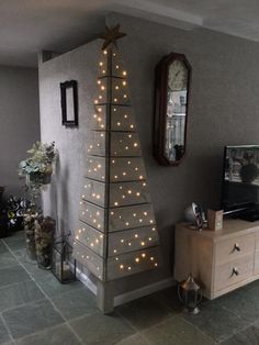 a living room with a small christmas tree on the wall and lights strung from it