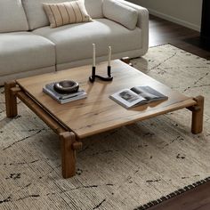 a living room with a couch, coffee table and books on the floor in front of it