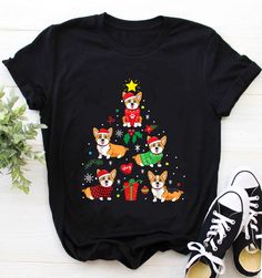 a t - shirt with dogs wearing christmas sweaters and stockings on it, sitting next to a pair of sneakers