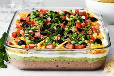 a large casserole dish filled with black olives, green peppers and cheese