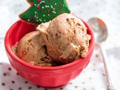 two scoops of ice cream in a red bowl with a christmas tree cookie on the side