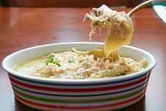 a spoon full of food is being lifted from a bowl with noodles and cheese in it