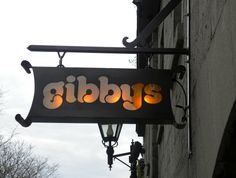 a sign hanging from the side of a building that says giba's on it