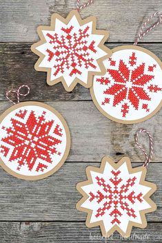 three wooden ornaments with red and white snowflakes hanging from them on a table