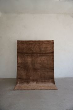 a brown rug sitting on top of a floor next to a white wall with a light fixture above it