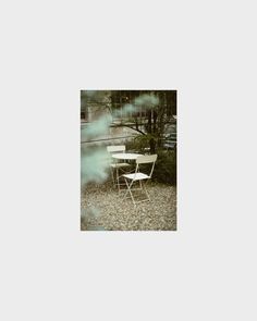 two white chairs sitting on top of a gravel field