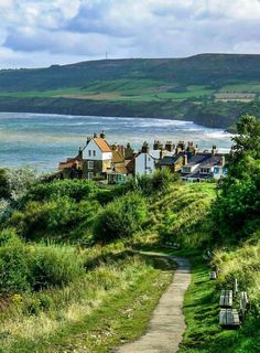 a path leading down to the beach with houses on it and water in the background