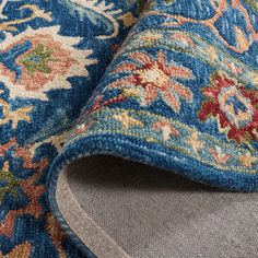 closeup of the blue and multicolored rug with floral design on it's edges