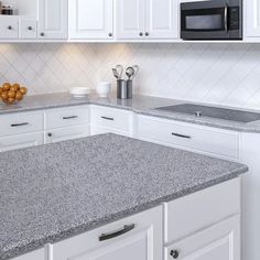 a kitchen with white cabinets and granite counter tops in front of a black microwave oven