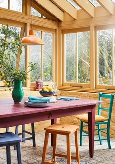 a dining room table and chairs in front of large windows with lots of natural light