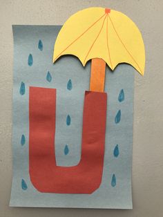 a piece of paper with an umbrella and raindrops on it, cut into the shape of a letter u