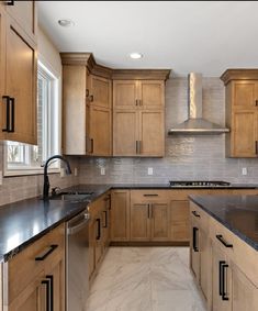 a large kitchen with wooden cabinets and black counter tops in the center, along with stainless steel appliances