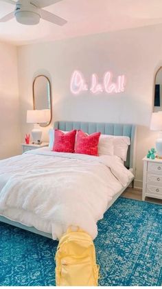 a bedroom with a blue rug, white bedding and two mirrors on the wall