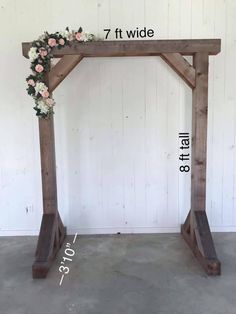 a wooden arch with flowers on it and measurements for the width in front of it