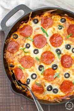 a pepperoni and olive pizza in a cast iron skillet on a wooden table