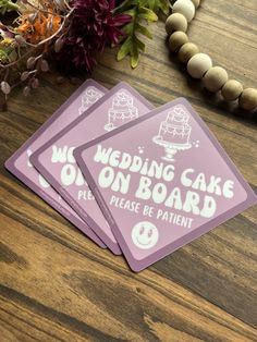 three wedding cake on board stickers sitting on a table next to flowers and beads