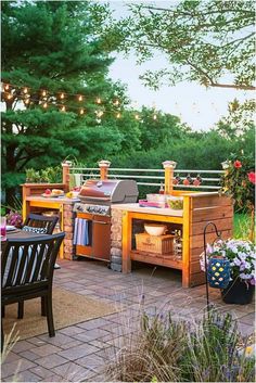 an outdoor bbq grill with lights strung above it and chairs on the patio next to it