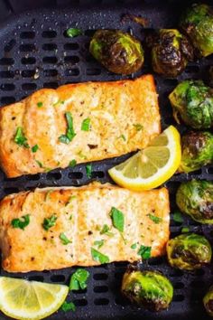 grilled salmon and brussel sprouts with lemon wedges on a grill