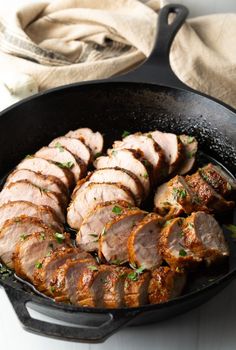 sliced pork in a cast iron skillet with parsley on the side, ready to be cooked