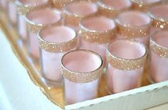 there are many pink glasses with gold glitters in the bottom one is filled with water