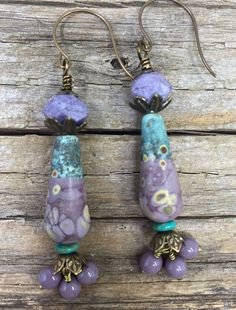 Handmade ceramic charms are topped with brass bead caps and purple Czech faceted beads. At the bottom of the ceramics there are small  turquoise spacer beads, bead caps with leaves and  dangles of three purple glass Czech beads. Earrings are three inches from the top of the ear wires with a drop length of 2.5 inches and a width of  .25 inches. Earrings Ceramic, Ceramic Earrings, Ceramic Necklace, Gilbert Az, Ceramic Earring, Bird Necklace, Pink Necklace, Bead Stringing, Purple Glass