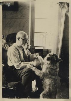 an old black and white photo of a man petting a dog