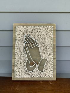 a wooden block with a hand and string design on the front, sitting on a table