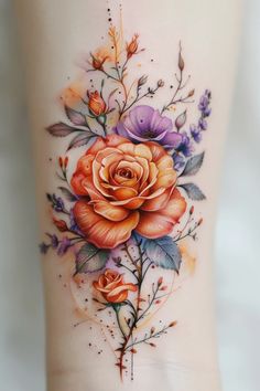 an orange rose tattoo on the side of a woman's leg with leaves and flowers