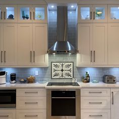 a kitchen with white cabinets and stainless steel range hood over the stove, oven and dishwasher