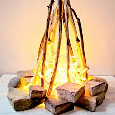 a fire pit made out of sticks and logs on top of a white tablecloth