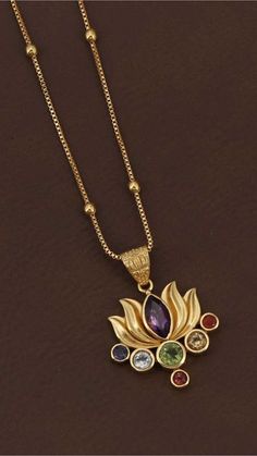 Gold chain necklace with a lotus pendant featuring colorful gemstones on a dark background. Spiritual Balance, Gem Pendant, Seven Chakra, Lotus Jewelry, Lotus Earrings, Lotus Pendant, Seven Chakras, Meaningful Jewelry, Chakra Stones