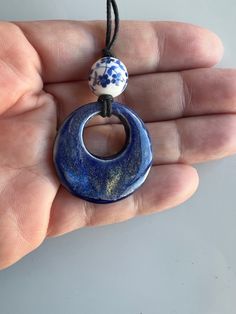 a hand holding a blue and white pendant