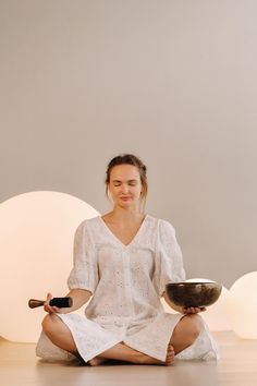 a woman sitting on the floor with a bowl and wine bottle in front of her