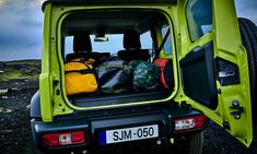 the back end of a green vehicle with luggage in it