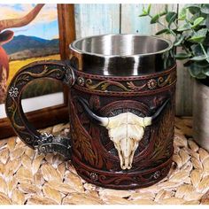 a cow skull is on the inside of a coffee mug with an intricate pattern and metal rim