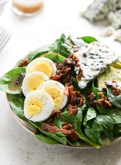 a salad with hard boiled eggs and spinach leaves on the side is ready to be eaten