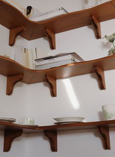 three wooden shelves with books and cups on them