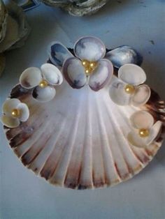 seashells are arranged on a plate with pearls and gold beads in the center