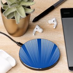 an iphone, earbuds and headphones on a wooden table next to a plant