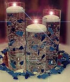 three candles are sitting in glass vases with blue and white confetti around them