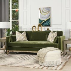 a living room with green couches and white rugs on the floor in front of a large window