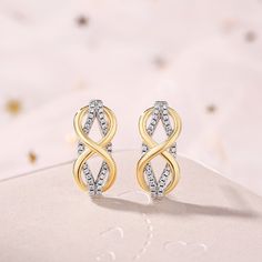 A beautiful way to tell her you'll love her for eternity, these stunning earrings offer that sentiment in shimmering style. Created in two-toned sterling silver, this design pairs polished yellow gold and stone-lined white gold ribbons together in an elegant looping infinity pattern. Celebrate your everlasting love with these darling fashion earrings.Carat Weight: 0.6 ctStone Size: 1 mmStone Type: Jeulia® StoneNumber of Stones: 60 Stone Shape: RoundStone Color: Diamond WhiteWeight: 3.97 gWidth: Elegant Hypoallergenic Infinity Earrings, Elegant Gold Infinity Earrings, Gold Infinity Earrings For Anniversary, Elegant Infinity Earrings For Anniversary, Gold Infinity Earrings For Formal Occasions, Elegant Infinity White Gold Earrings, Elegant White Gold Infinity Earrings, Infinity Pattern, Silver Earrings Online