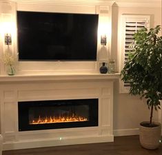 a living room with a large television mounted above the fireplace and a potted plant next to it