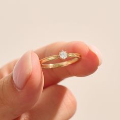 a woman's hand holding a gold ring with a diamond on the middle finger