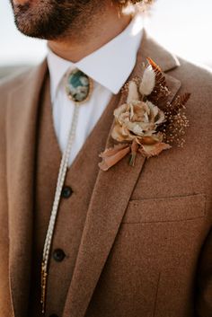 a man wearing a brown suit and flower boutonniere on his lapel