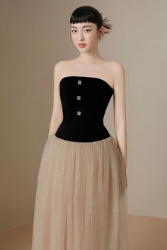 a woman wearing a black and beige dress with a tulle skirt on the bottom